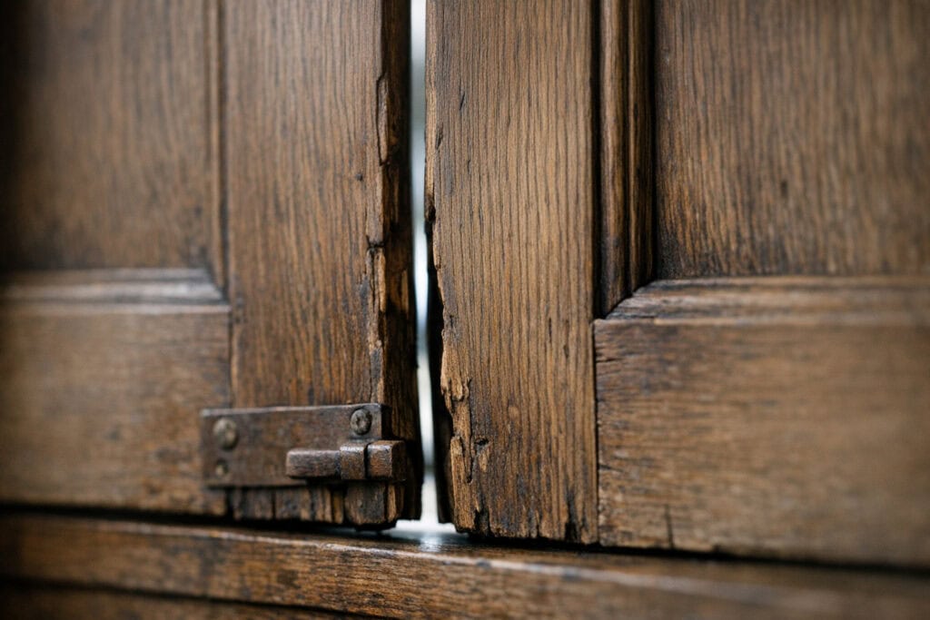Verweerde houten luiken die door kromtrekking niet meer sluiten
