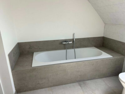 Moderne badkamer met een bad en grijze wandafwerking