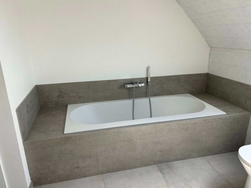 Moderne badkamer met een bad en grijze wandafwerking