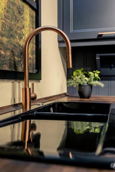 Moderne keuken met zwarte spoelbak en koperen kraan