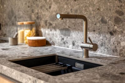 Moderne keuken met natuurstenen werkblad, een spoelbak en zwarte keukenkraan
