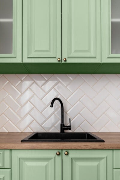 Groene keuken met zwarte spoelbak en zwarte keukenkraan