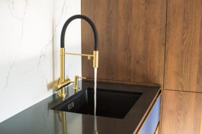 Moderne keuken met zwarte spoelbak en gouden kraan